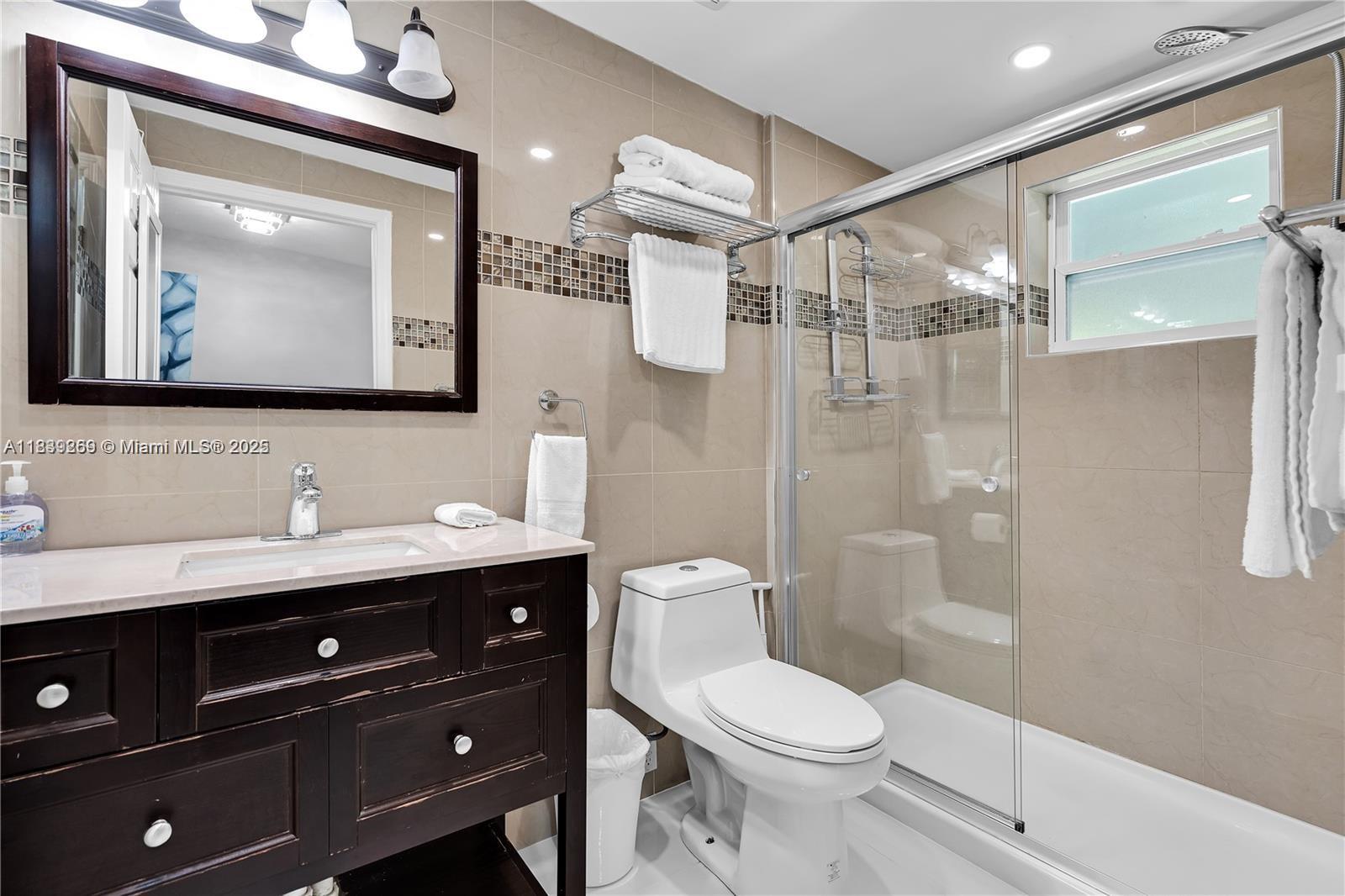 1761 Southwest 14th Street Miami, FL 33145 - Photo 32 of 37 a bathroom with a toilet a sink a glass door shower and mirror