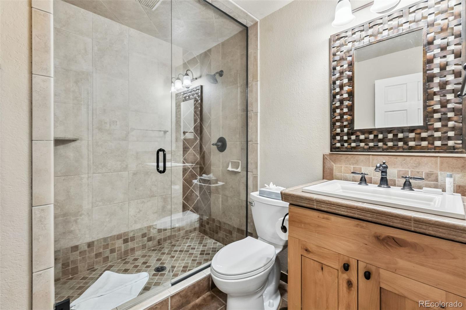 46 Indiana Creek Road Breckenridge, CO 80424 - Photo 33 of 50 a bathroom with a granite countertop sink a toilet a mirror and shower