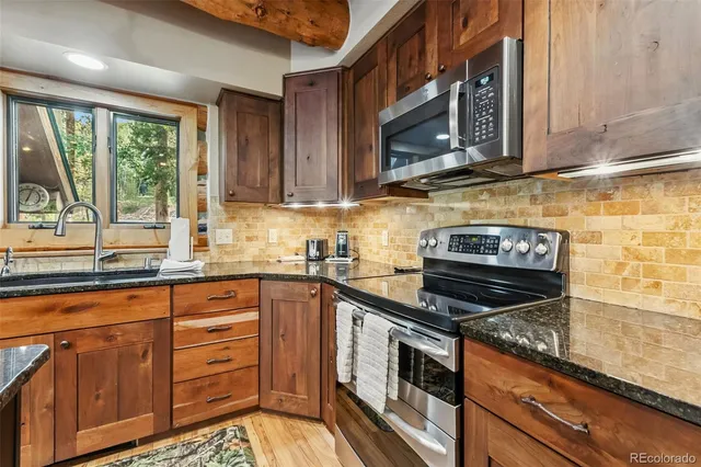 a kitchen with granite countertop a stove top oven microwave and cabinets