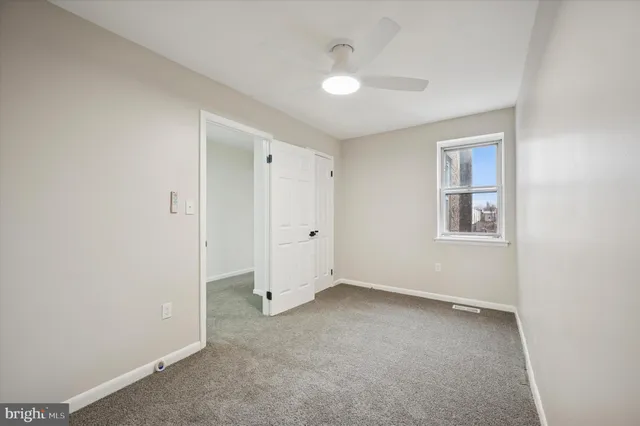 an empty room with a chandelier fan and a window