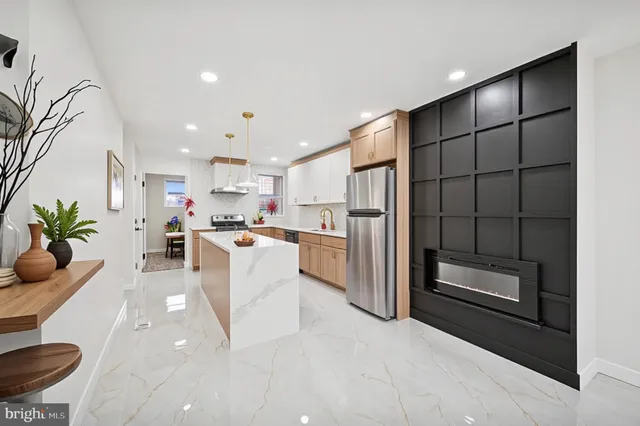 a living room with stainless steel appliances kitchen island granite countertop a refrigerator a oven a sink with wooden cabinets and glass door