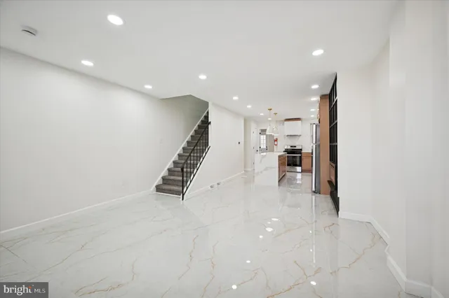a kitchen with granite countertop a sink stainless steel appliances white cabinets and a refrigerator