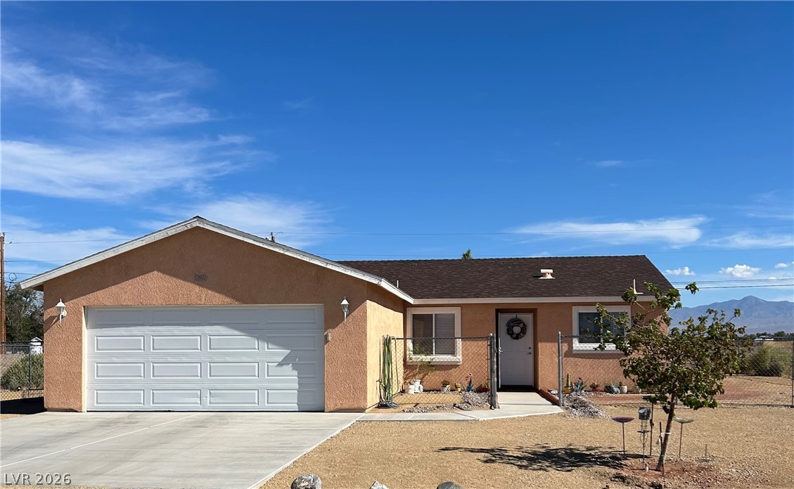 Classic stucco exterior pairs with a spacious concrete driveway under wide desert skies.