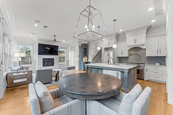 a kitchen with stainless steel appliances granite countertop a stove a sink a refrigerator a couch and a dining table with wooden floor