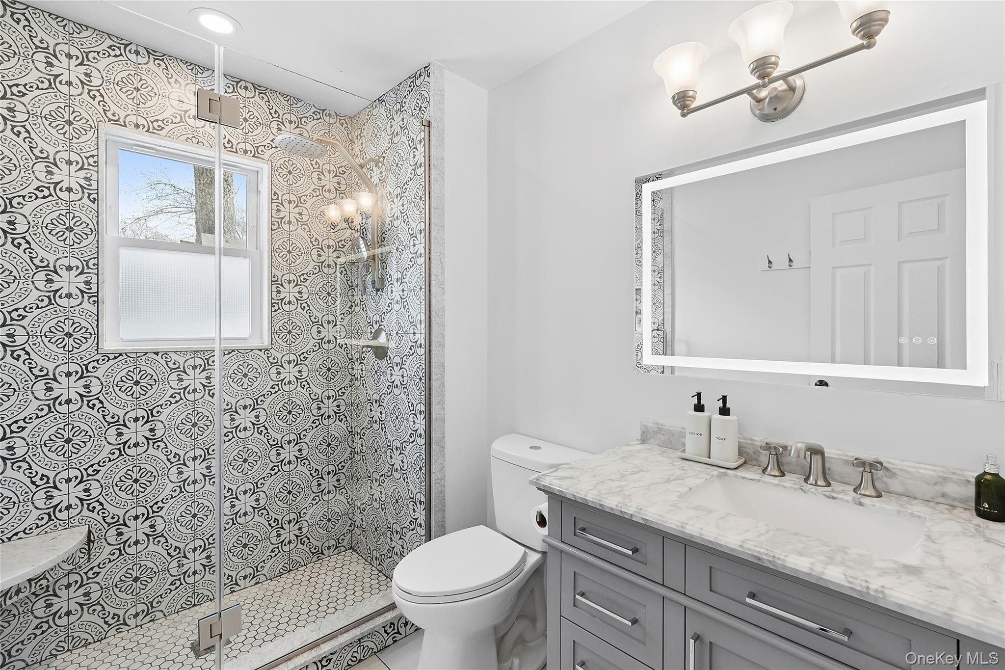 24 Woodridge Road Hampton Bays, NY 11946 - Photo 8 of 18 a bathroom with a granite countertop sink a toilet and a mirror