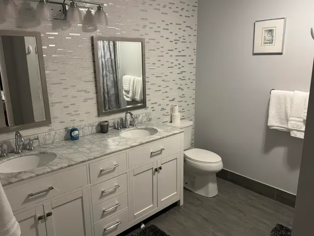 a bathroom with a granite countertop toilet sink and mirror