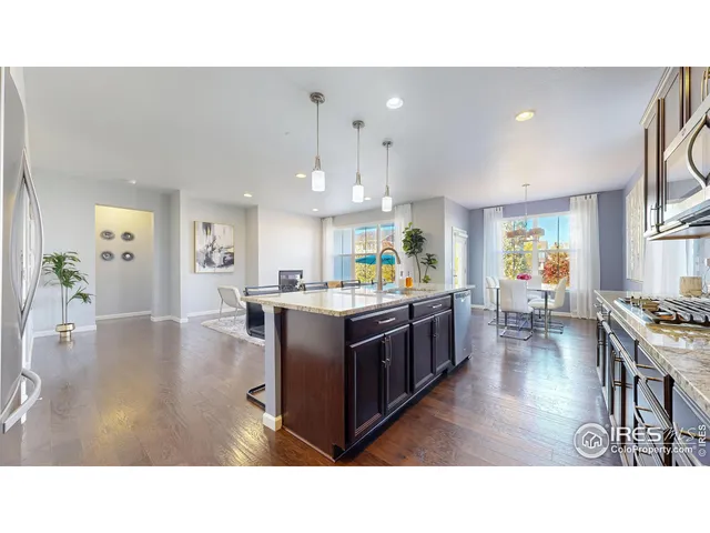 a living room with stainless steel appliances kitchen island granite countertop a table chairs and a refrigerator