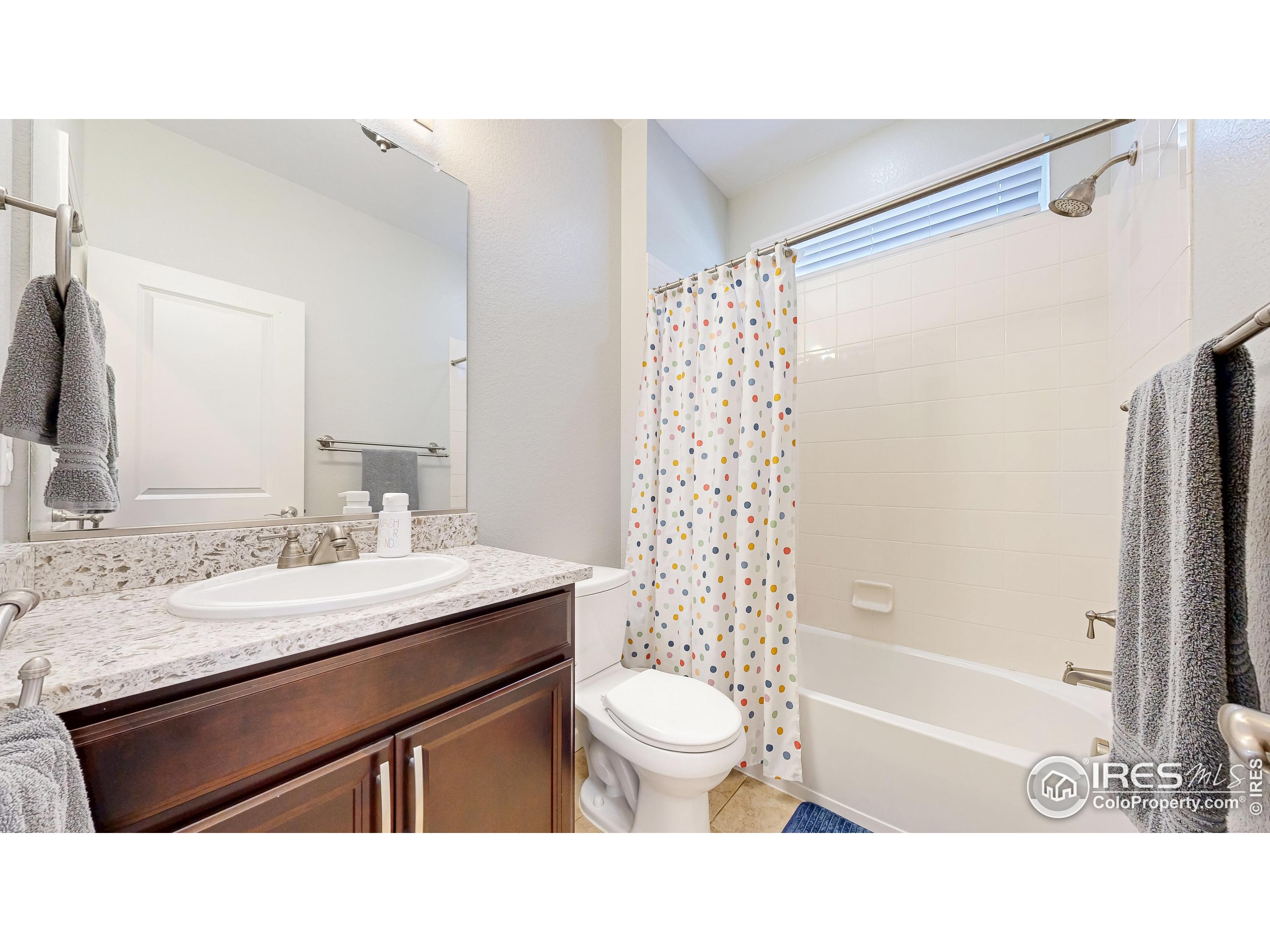 6794 Spring Rain Road Timnath, CO 80547 - Photo 19 of 49 a bathroom with a sink a toilet a mirror a bathtub and shower