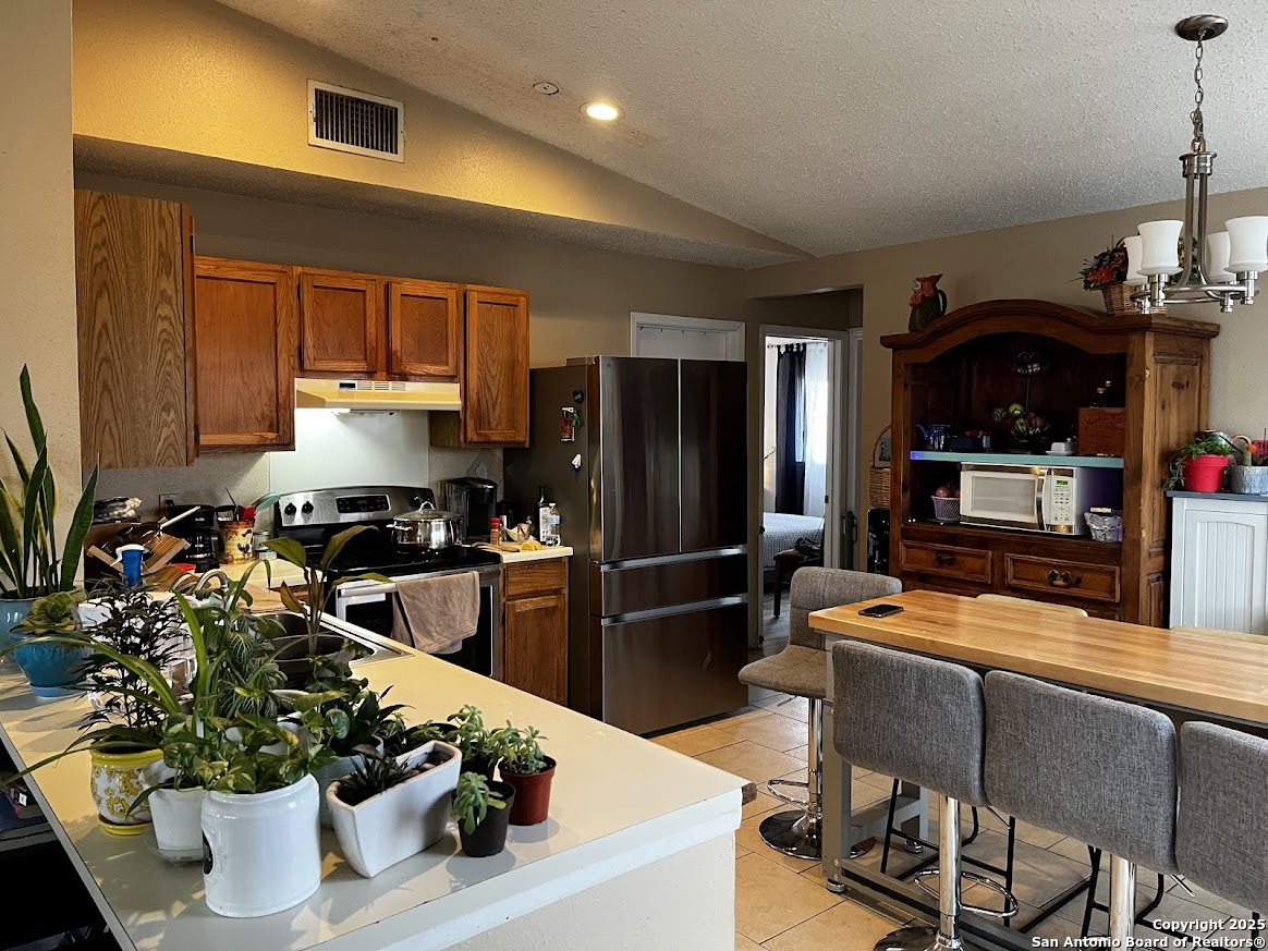 6613 Pebble Spring Drive San Antonio, TX 78249 - Photo 8 of 11 a kitchen with stainless steel appliances kitchen island granite countertop a refrigerator and a stove top oven