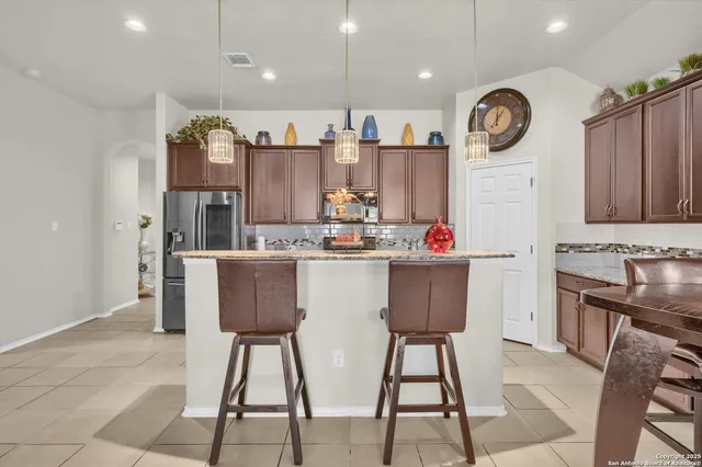 a kitchen with stainless steel appliances granite countertop a dining table chairs sink and cabinets