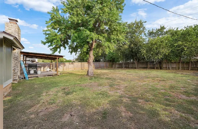 a view of a house with backyard and a tree