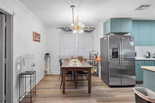 a kitchen with stainless steel appliances a dining table chairs refrigerator and cabinets