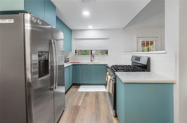 a kitchen with stainless steel appliances granite countertop a refrigerator and a sink