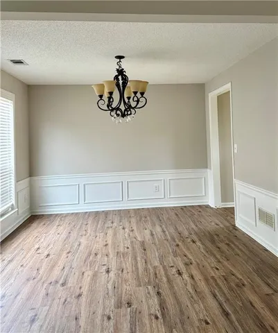 a view of an empty room with wooden floor and window