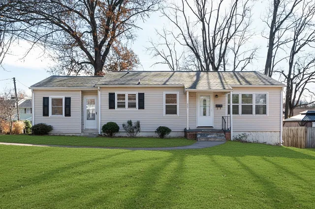 a front view of a house with a garden and trees