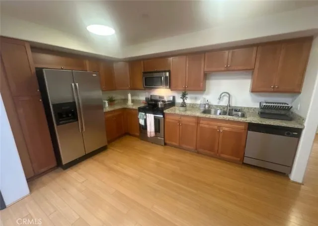 a kitchen with stainless steel appliances granite countertop a refrigerator a sink a stove top oven a sink and dishwasher