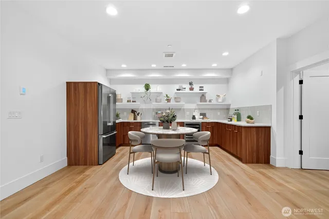 a living room with stainless steel appliances furniture a dining table and a refrigerator