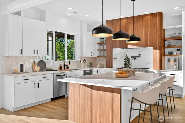 a kitchen with stainless steel appliances granite countertop a sink a microwave oven a stove and white cabinets