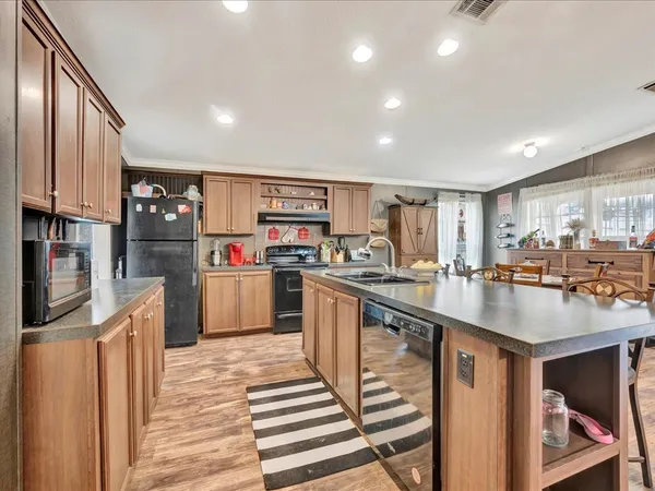 a kitchen with stainless steel appliances granite countertop a refrigerator a stove and a sink with wooden floor