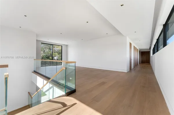 a view of hallway with window and wooden floor