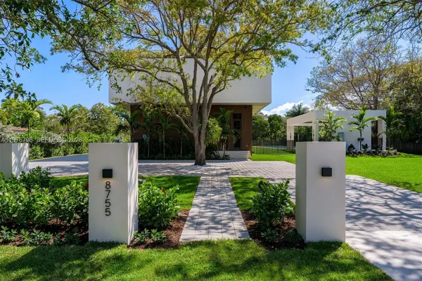 a front view of a house with a garden and trees