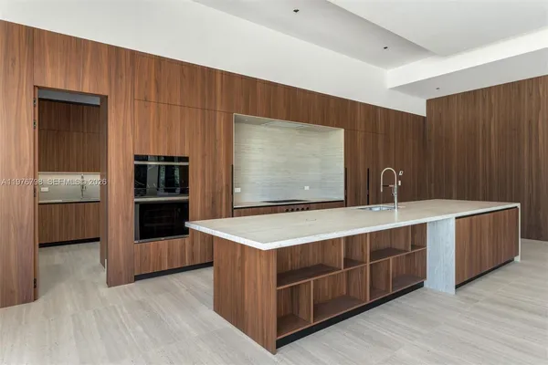 a large kitchen with stainless steel appliances a large counter top and a refrigerator