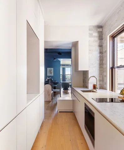 a large white kitchen with a sink and dishwasher a stove with wooden floor