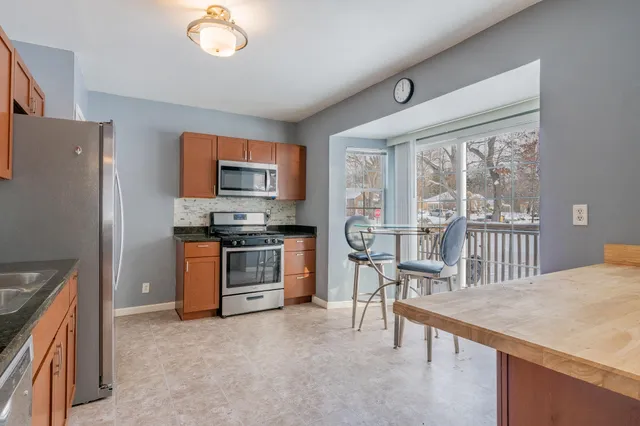a kitchen with granite countertop a stove a sink a dining table and chairs