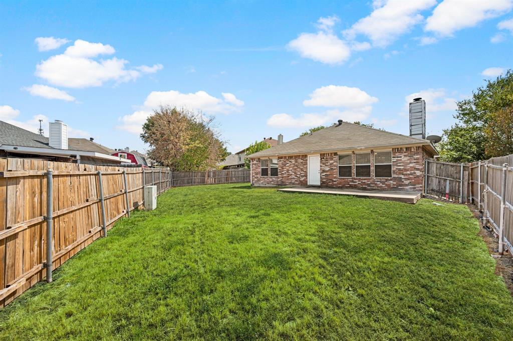 5509 Timber Ridge Court Watauga, TX 76137 - Photo 26 of 28 Expansive backyard featuring a manicured lawn, wood fencing, and a brick exterior