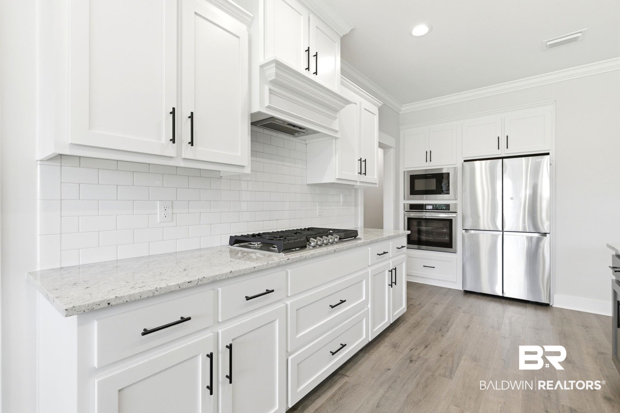 12132 Exbury Way Daphne, AL 36527 - Photo 12 of 47 Kitchen with stainless steel appliances, light stone countertops, white cabinetry, ornamental molding, and backsplash