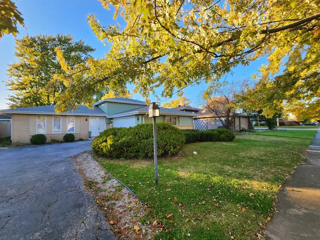 a view of a house with a big yard plants and large tree