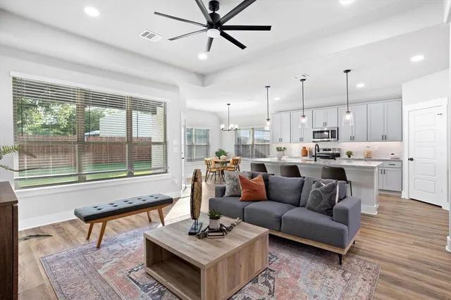 a living room with furniture and a large window with kitchen view