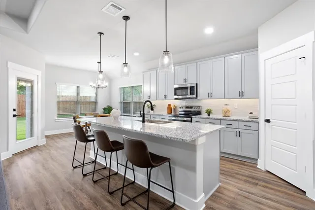 a kitchen with stainless steel appliances granite countertop a white cabinets and wooden floors