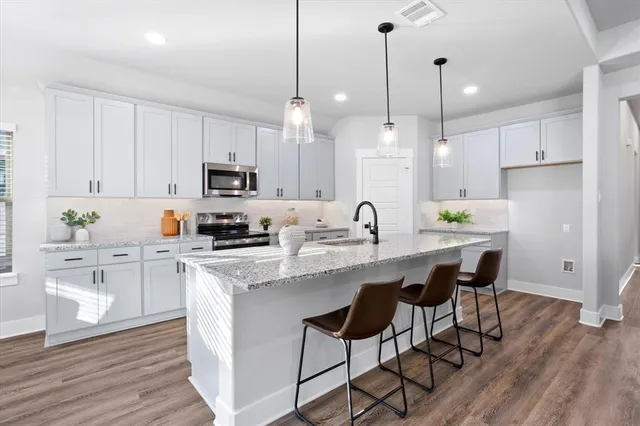 a kitchen with stainless steel appliances kitchen island a white table chairs and a sink