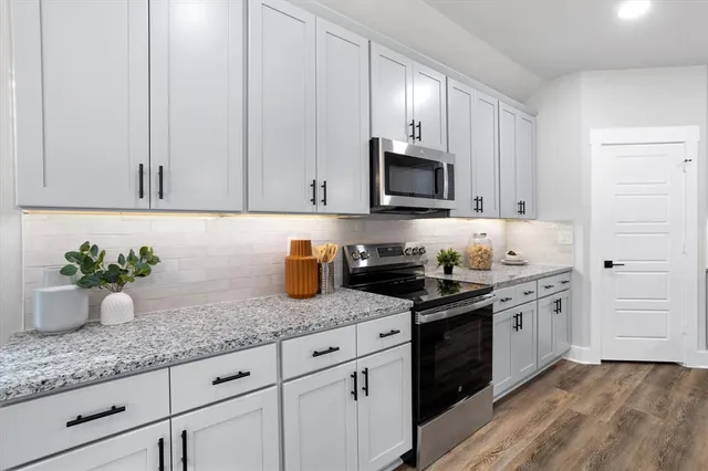 a kitchen with granite countertop white cabinets and stainless steel appliances