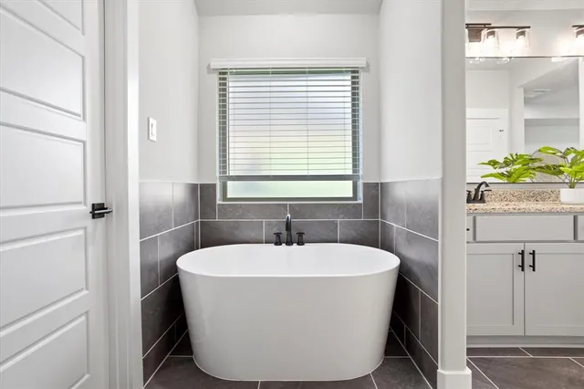 a white bath tub sitting in a bathroom next to a window