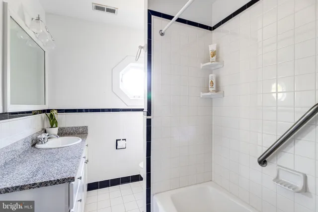 a bathroom with a granite countertop sink a mirror and shower