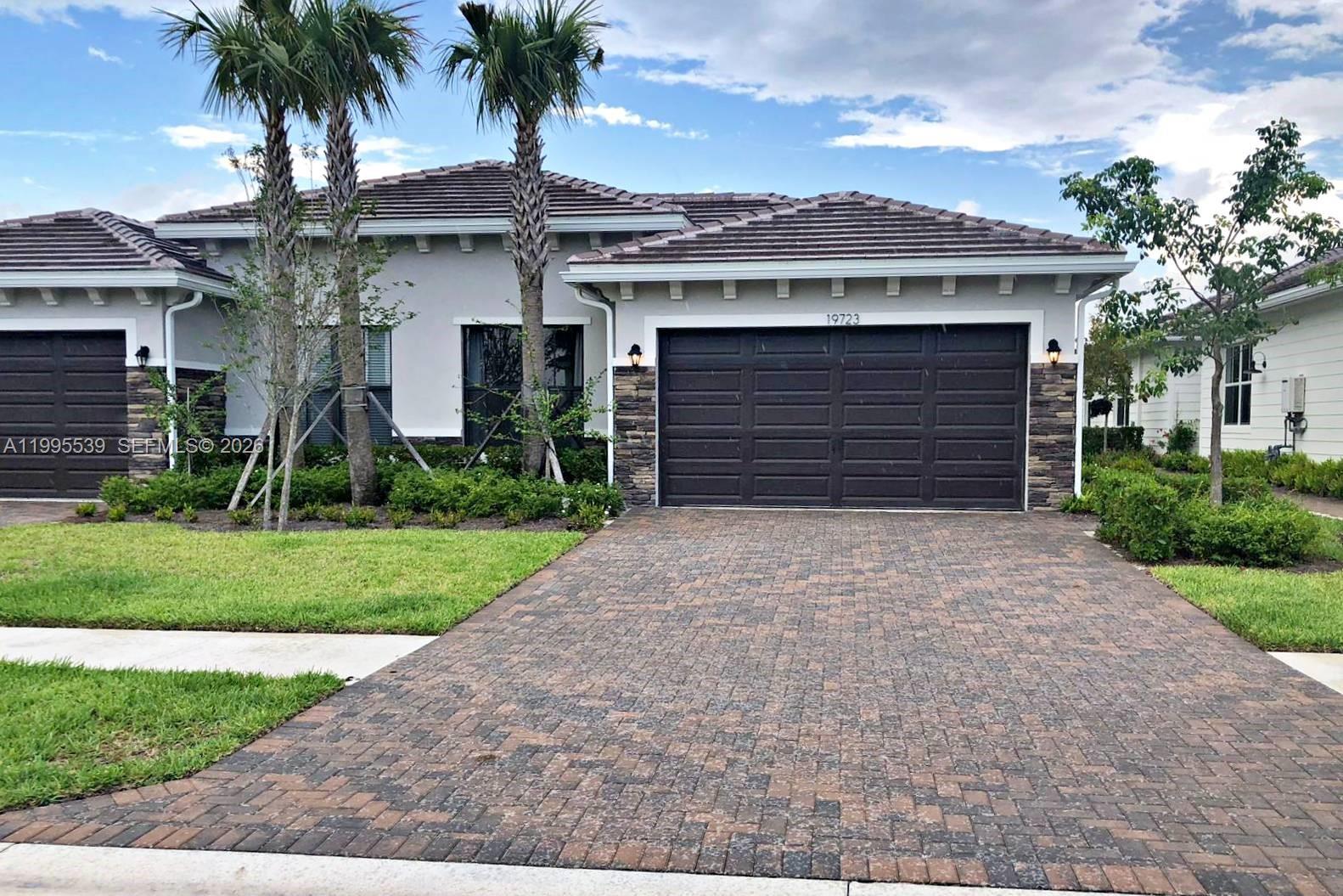 front view of a house with a yard and palm trees
