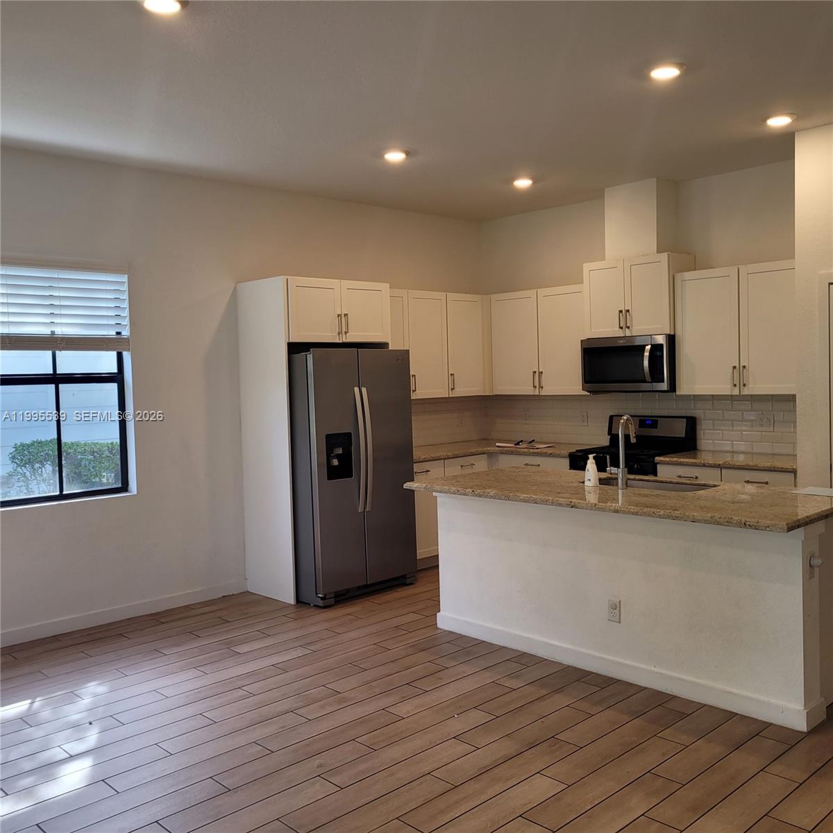 19723 Weathervane Way Loxahatchee, FL 33470 - Photo 5 of 24 a kitchen with stainless steel appliances granite countertop a refrigerator stove top oven and sink with wooden floor