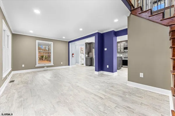 an empty room with kitchen and natural light