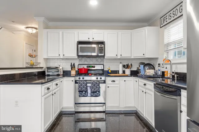 a kitchen with stainless steel appliances granite countertop a sink a stove top oven and white cabinets