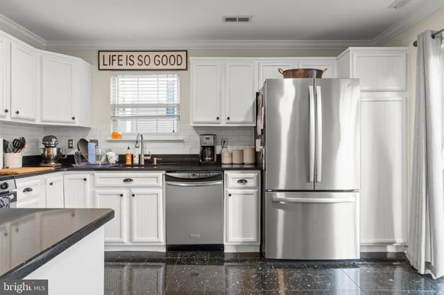 a kitchen with granite countertop stainless steel appliances a refrigerator sink and cabinets