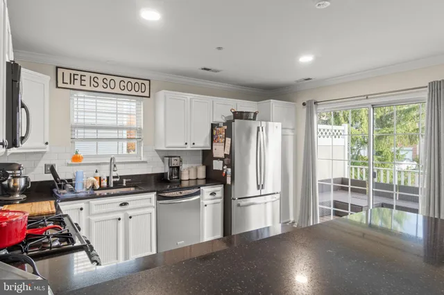 a kitchen with sink a refrigerator and white cabinets