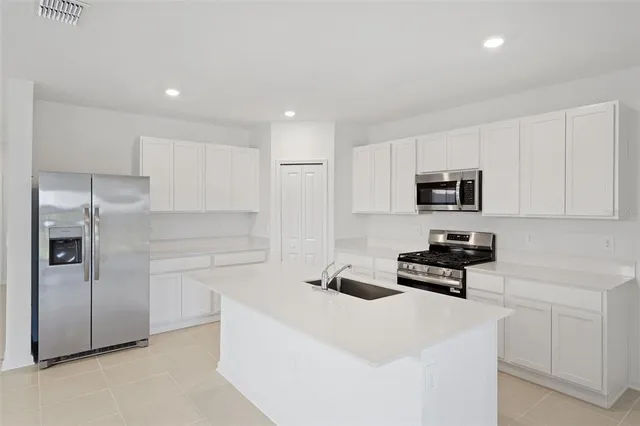 a kitchen with stainless steel appliances a refrigerator stove and white cabinets