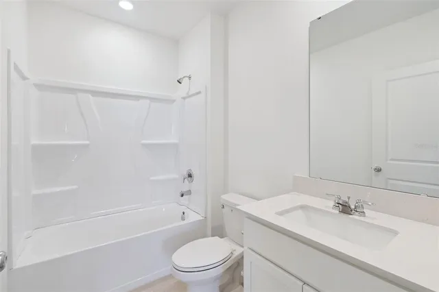 a bathroom with a granite countertop bathtub shower sink vanity mirror and toilet