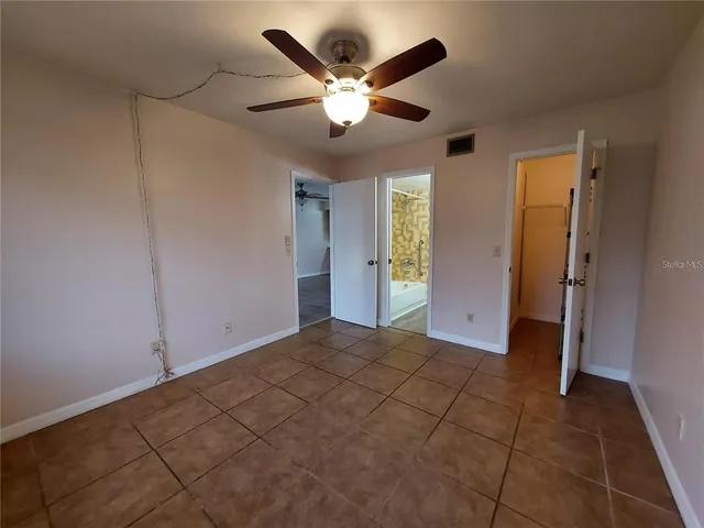 a view of an empty room with closet and a ceiling fan
