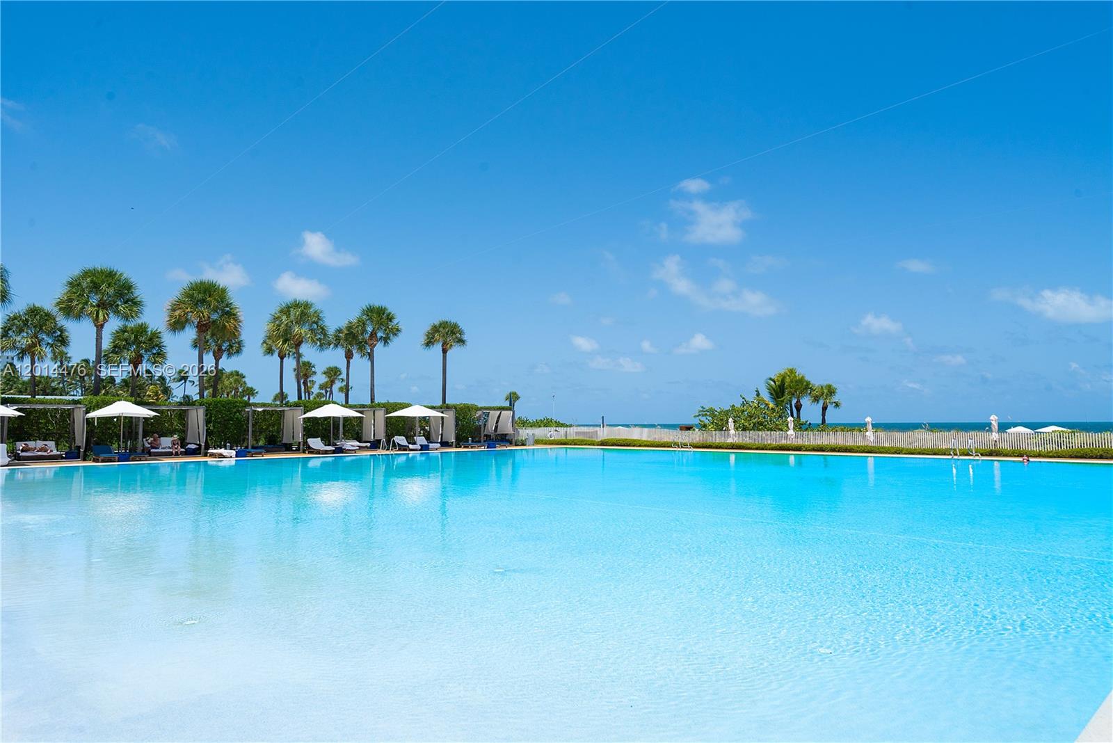 360 Ocean Drive, Unit 1106S Key Biscayne, FL 33149 - Photo 34 of 67 Resort-Style Pool – The pool area features a large beachfront pool surrounded by cabanas, lounge seating, and palm trees. Ocean views beyond the pool create a serene resort-style setting.