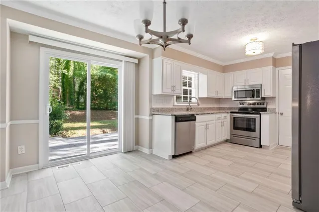 a kitchen with stainless steel appliances a stove a sink dishwasher a refrigerator and white cabinets with wooden floor