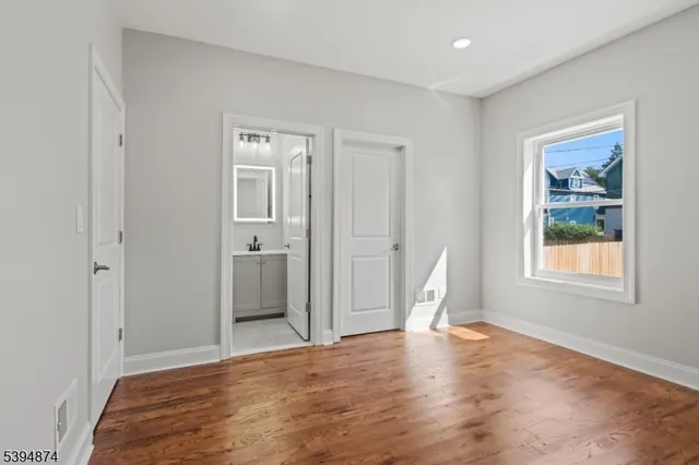 a view of empty room with window and wooden floor