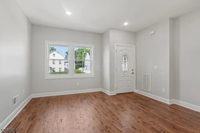an empty room with wooden floor and windows